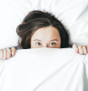 woman peaking from underneath the covers