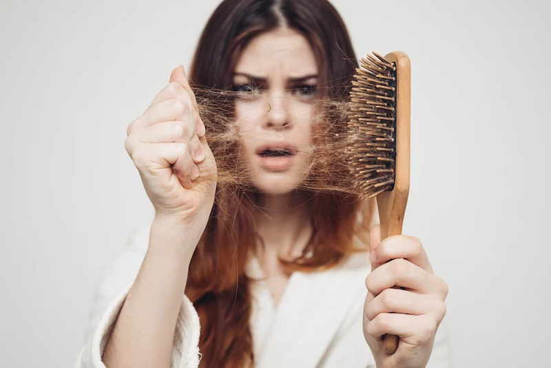 woman pulling hair from her hair brush