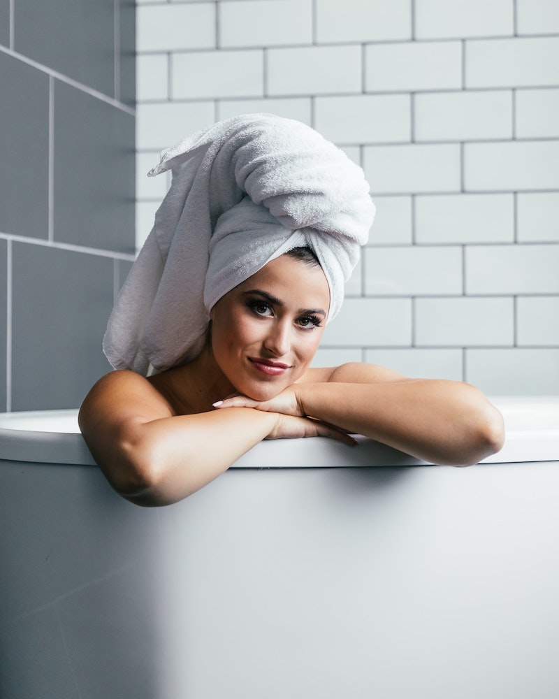 woman sitting in bath with towel on her head
