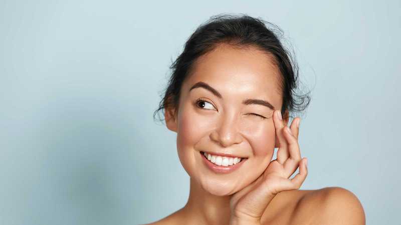 woman with one eye closed and glowing skin