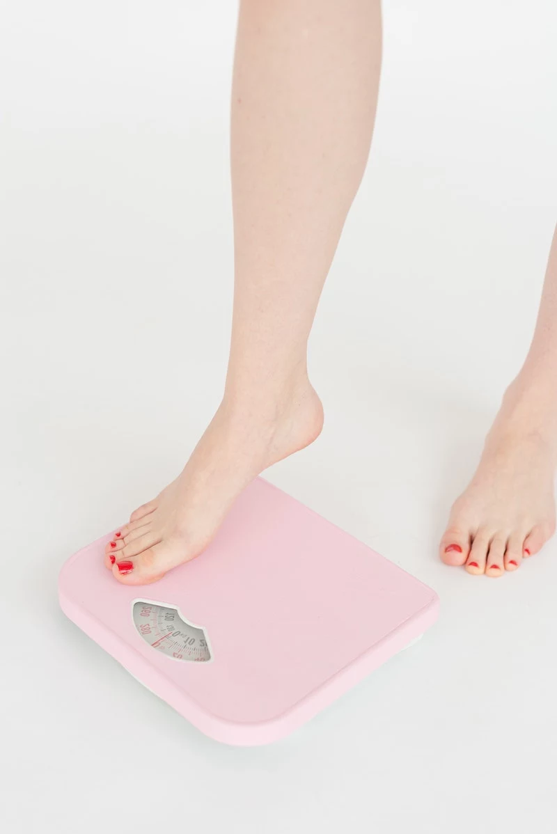 woman with painted toe nails stepping on a scale