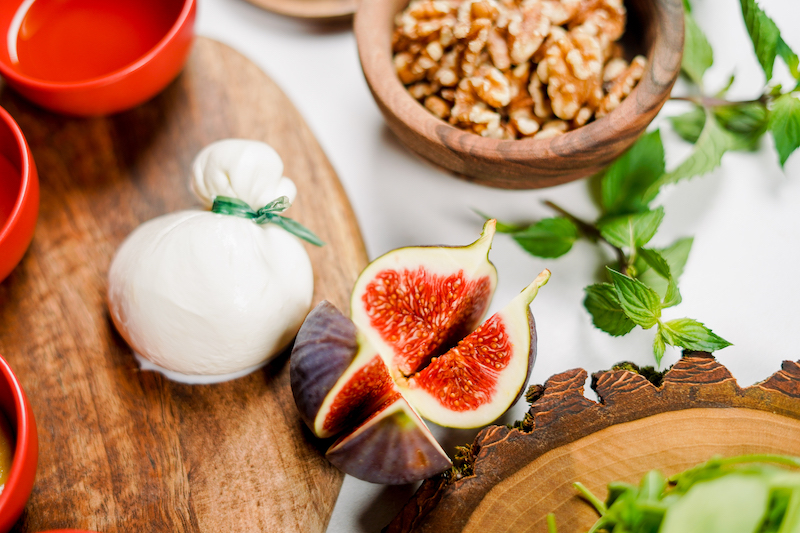burrata cheese figs and walnuts on a board