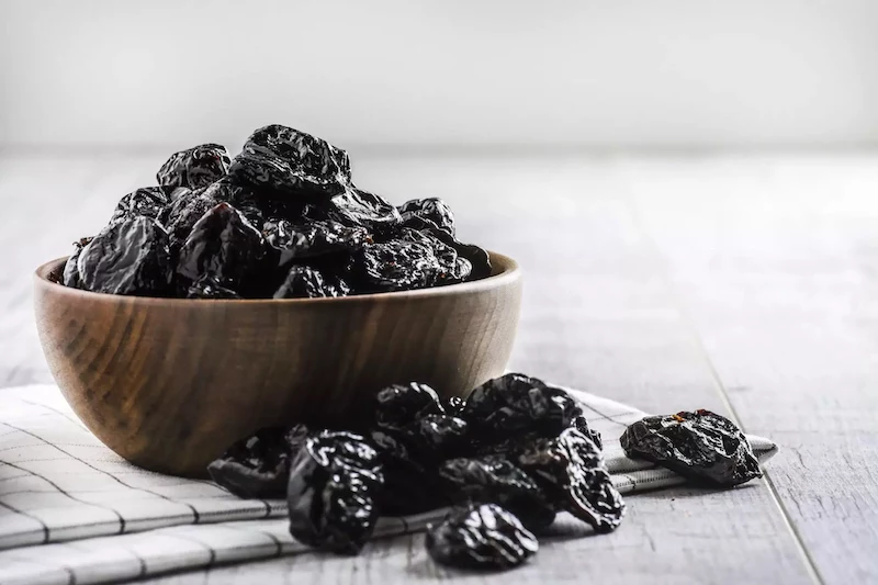dried black prunes in a wooden bowl copy