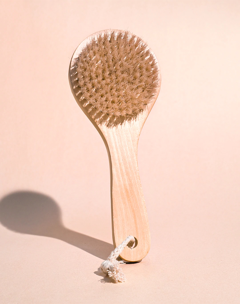dry brushing brush with bristles and long handle on pink background