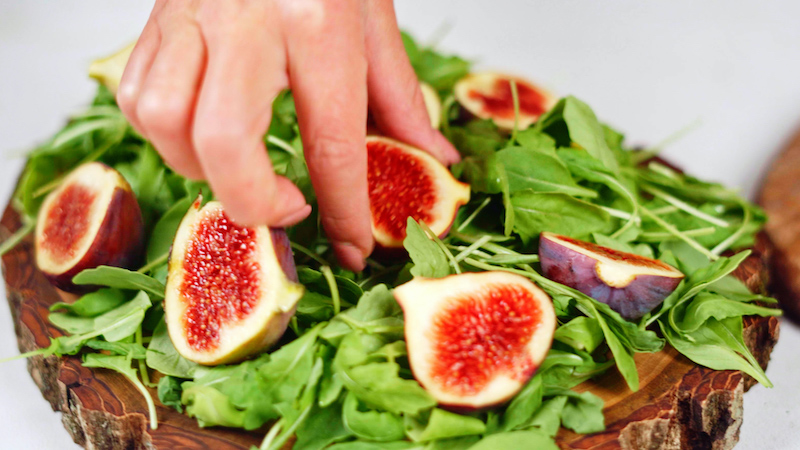 figs and arugula on a wooden board