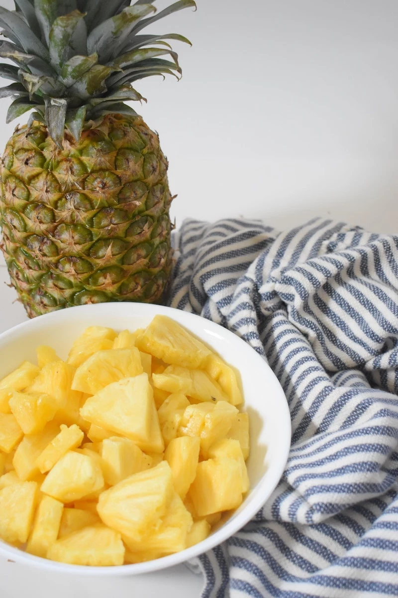 foods that boost energy pineapple slices in a bowl with a pineapple in the back