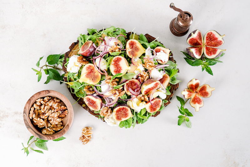 fresh summer salad with figs on a wooden cutting board