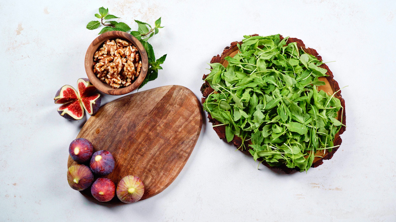 ingredients for salad arugula figs walnuts and cutting board