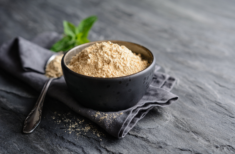 dietary supplement, maca root powder in a bowl and spoon with copy space
