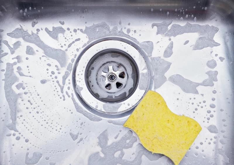 close up sink drain and yellow sponge