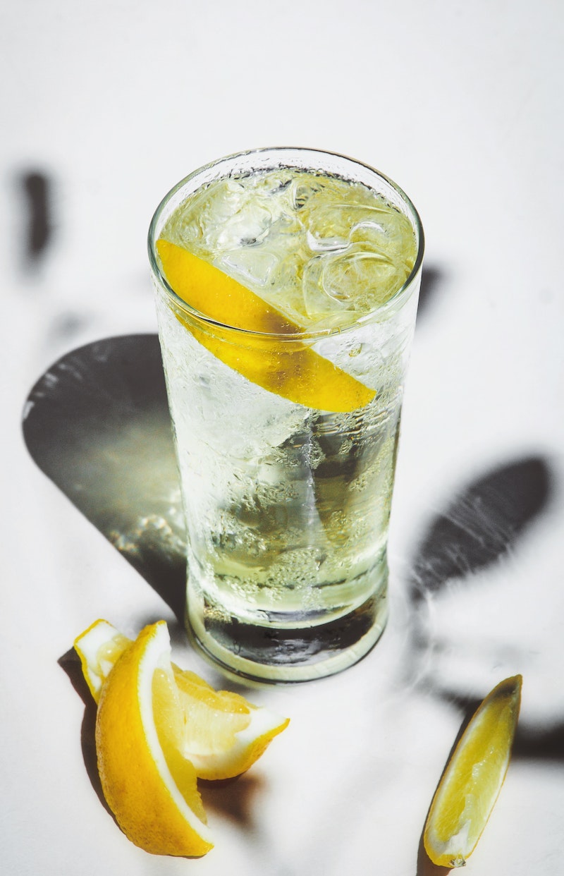 tall glass of soda with ice and lemon slices