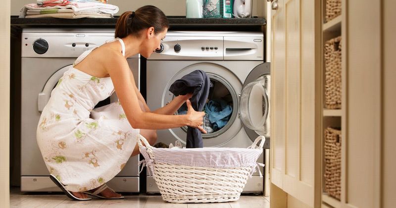 woman crouched in front of a washing machine