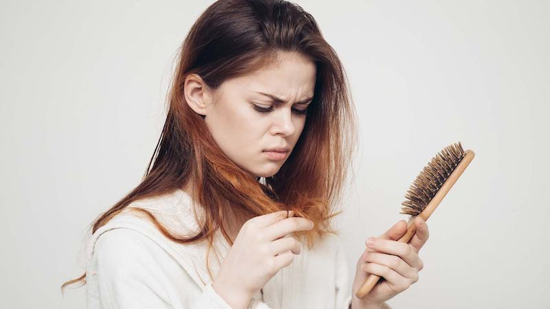 woman holding a hair brush looking at hair ends