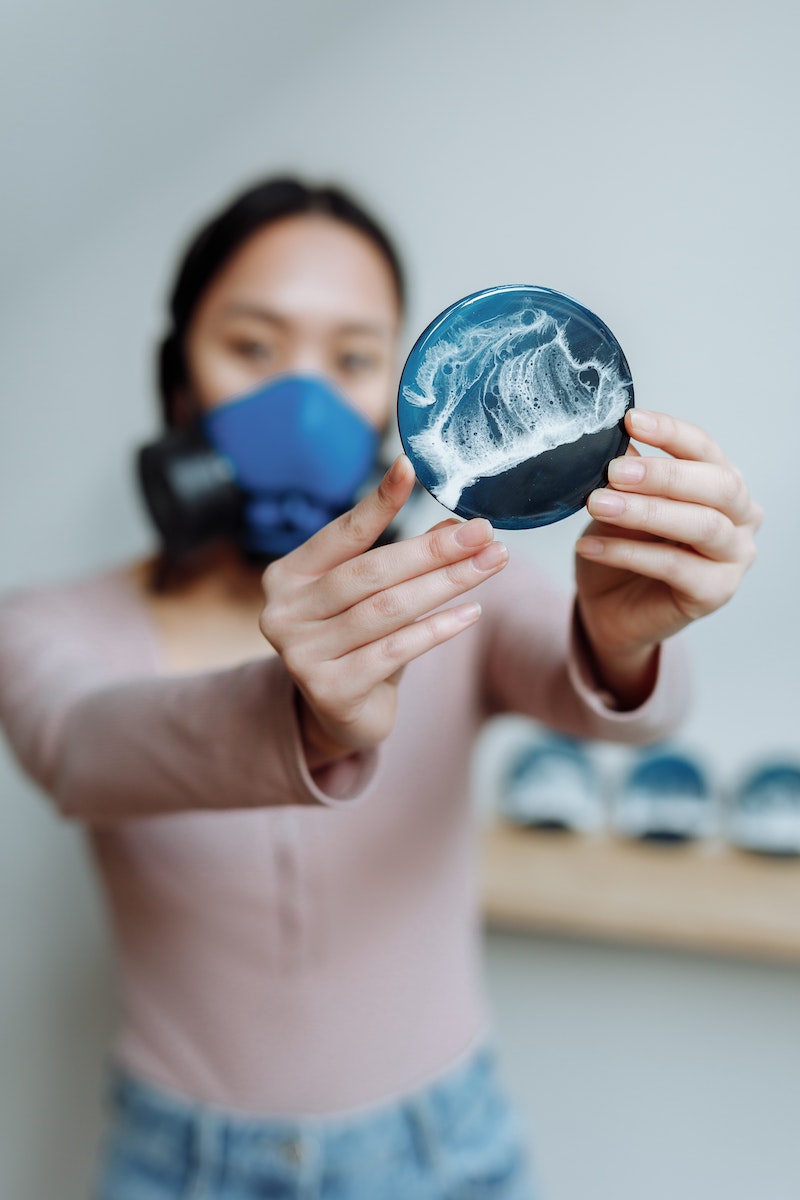 woman holding a resin blue and white coaster