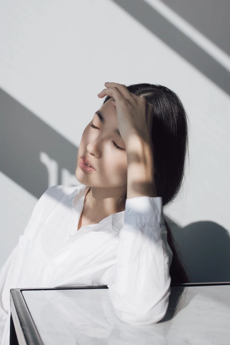 woman with clear skin using her hand as protection from the sun