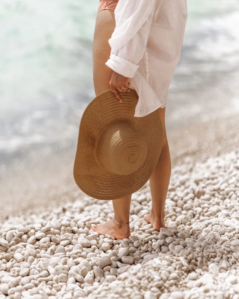 beach list woman holding a straw hat