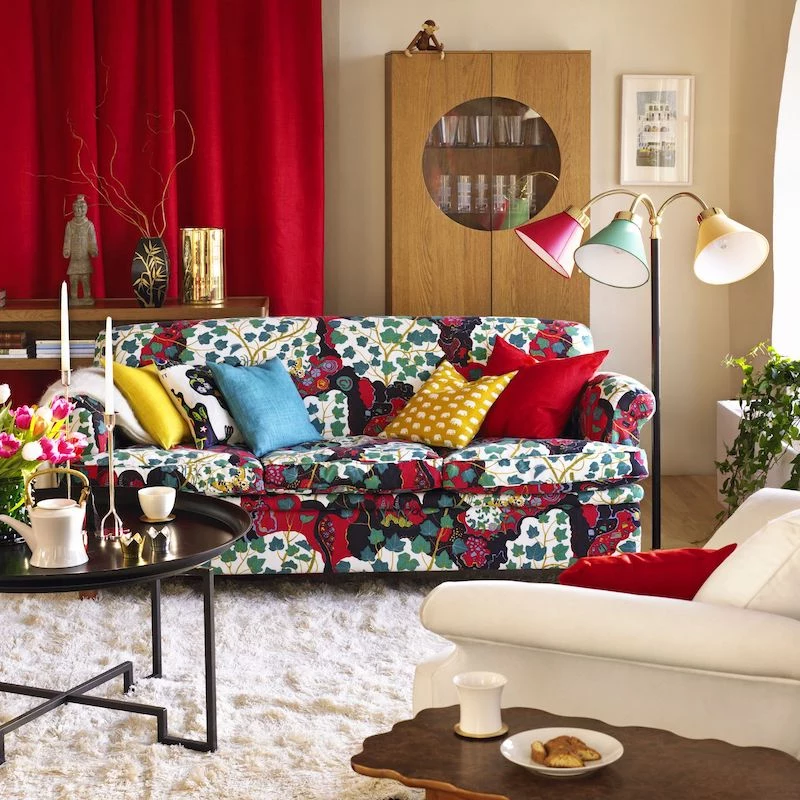 colorful couch with red drapes behind and tri colored lamps