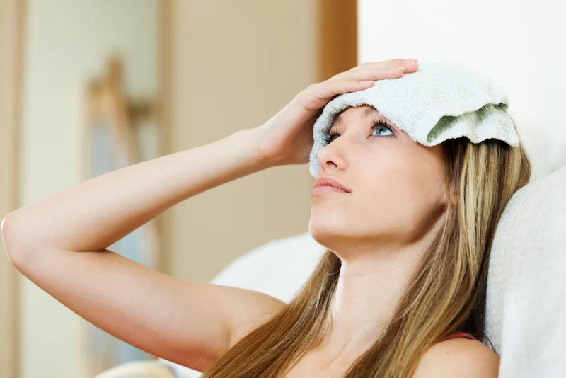 get rid of a headache woman with a warm compress on her forehead
