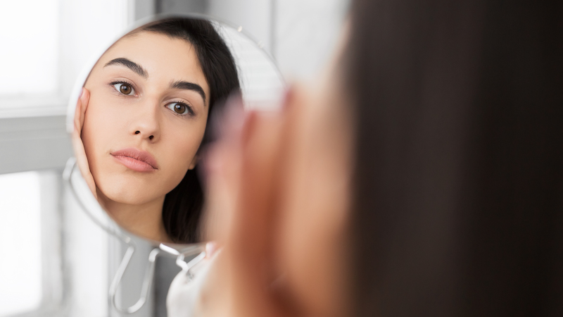 girl touching face looking at perfect skin in mirror panorama