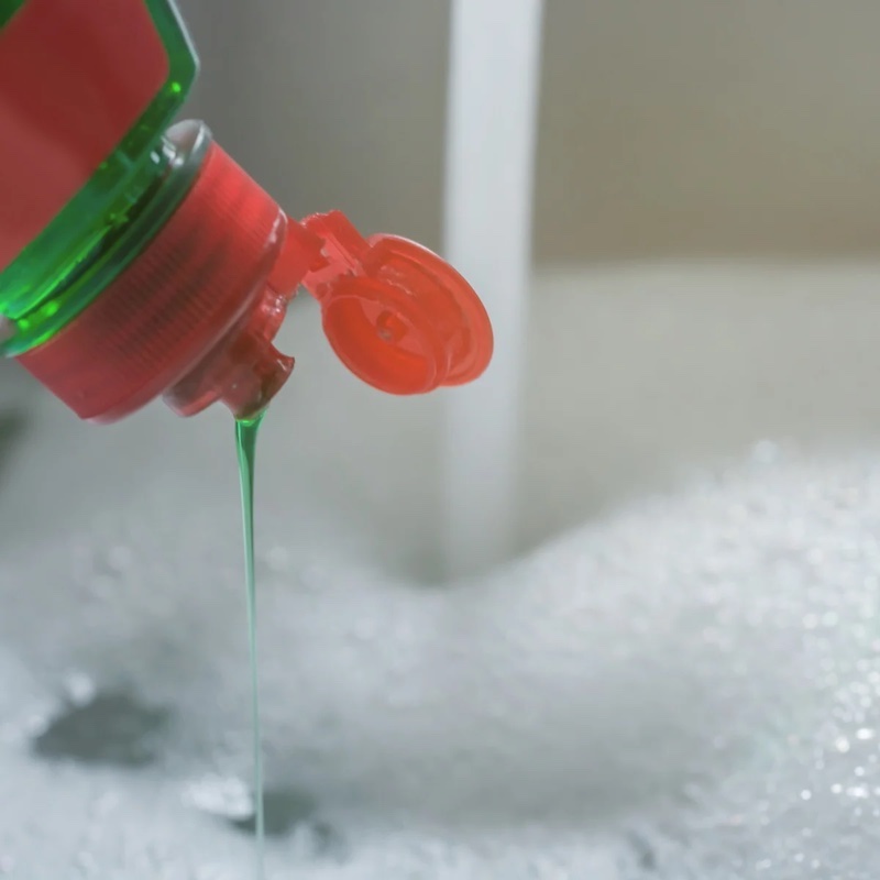 green dish soap being poured in the sink