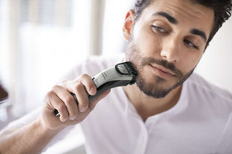 man using trimmer on his beard