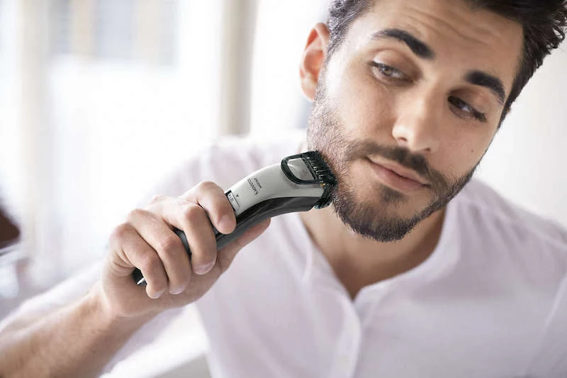 man using a trimmer on his beard