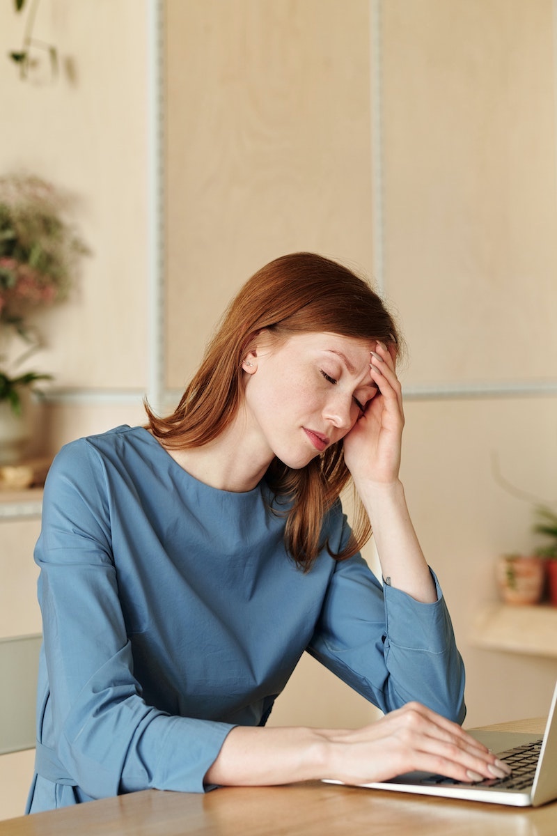 red head woman working with a headache in front of the computer