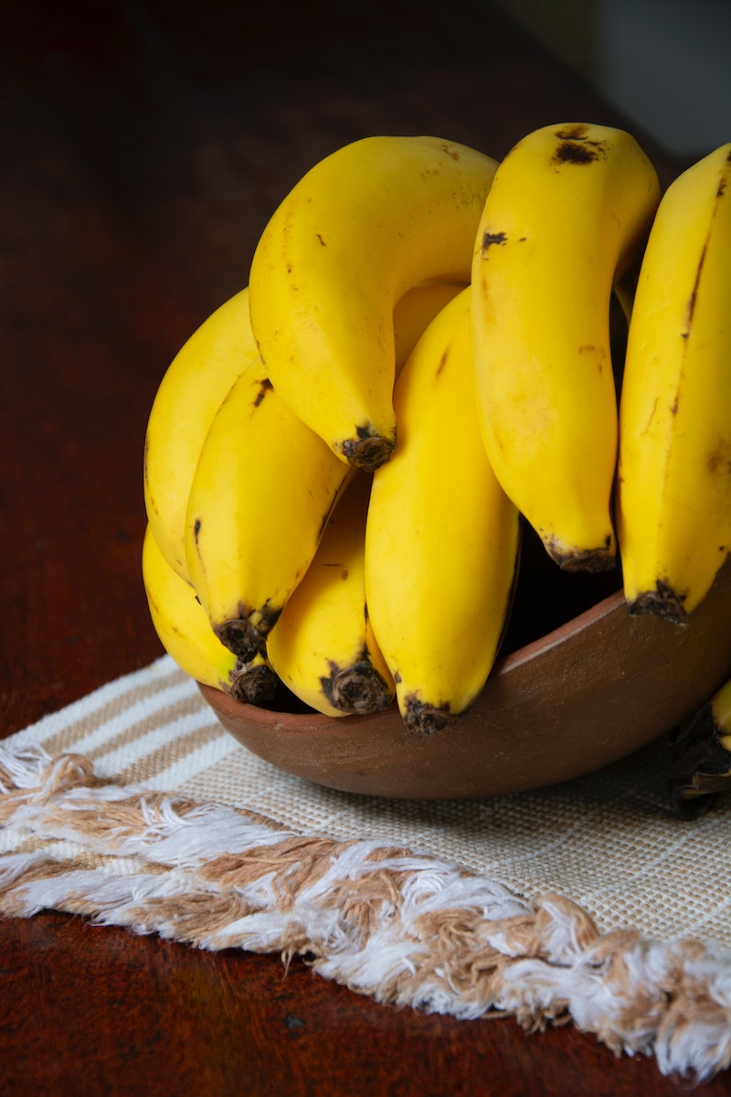 ripe yellow banans sitting in a wooden bowl