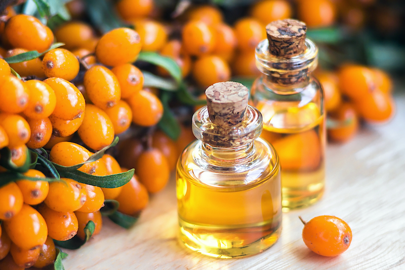 sea buckthorn oil fruits next to bottle of oil
