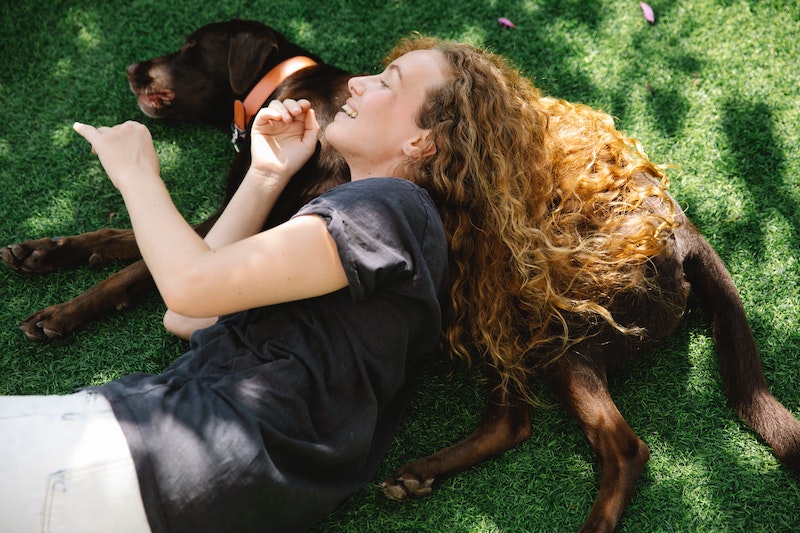 woman and her brown dog laying in the tree shade
