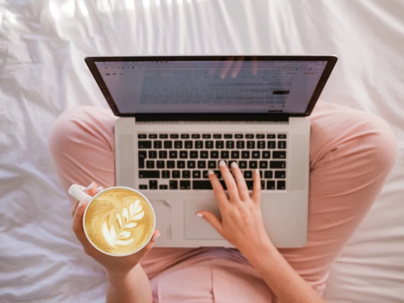 woman holding her coffee and working on her laptop