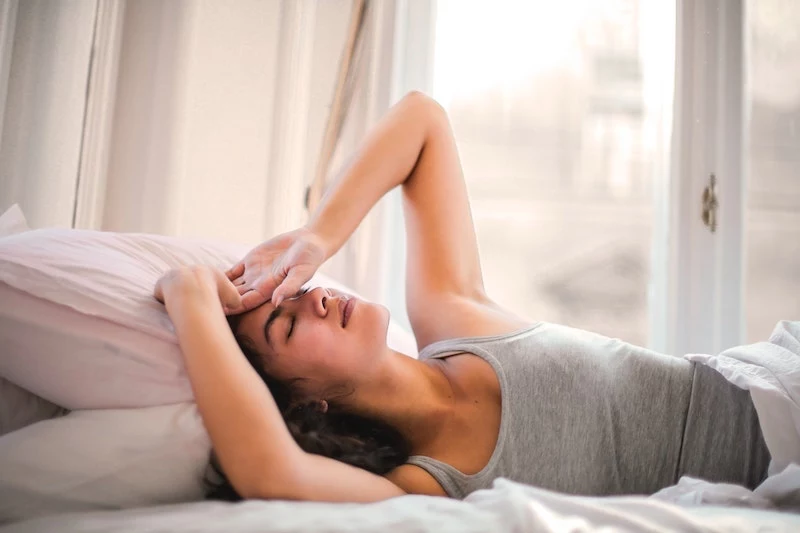 woman lying in bed with headache