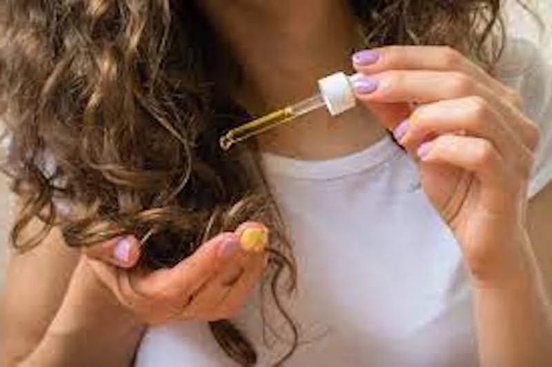 woman puting oil on her hair for hair growth