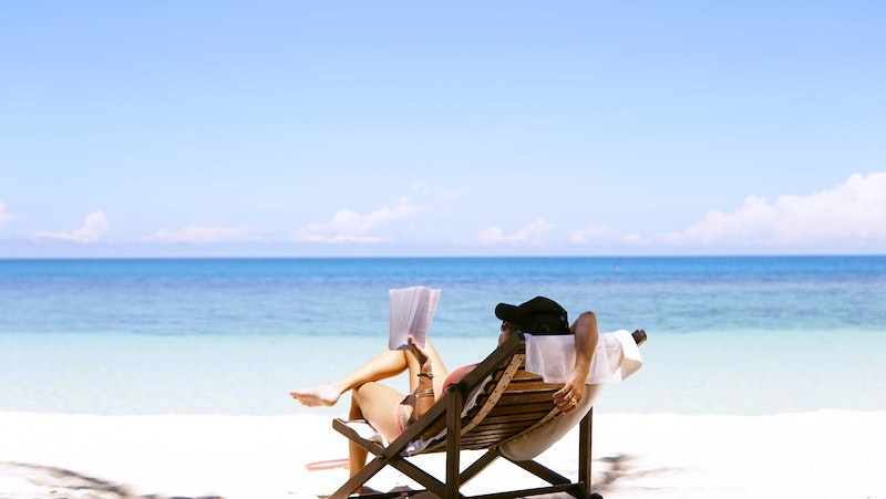 woman sitting on a beach chair reading a book
