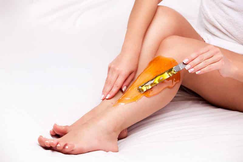 woman waxing her leg at home with sugar