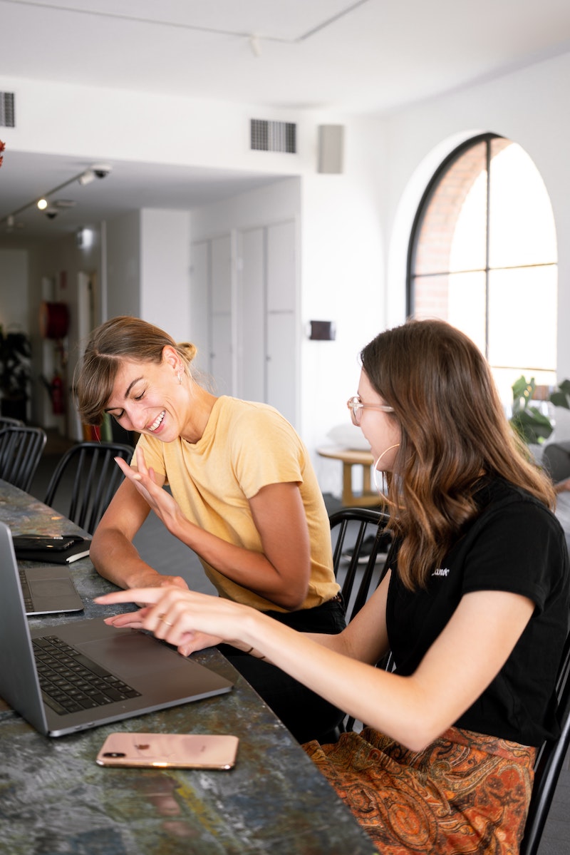 women talking together in front of laptops