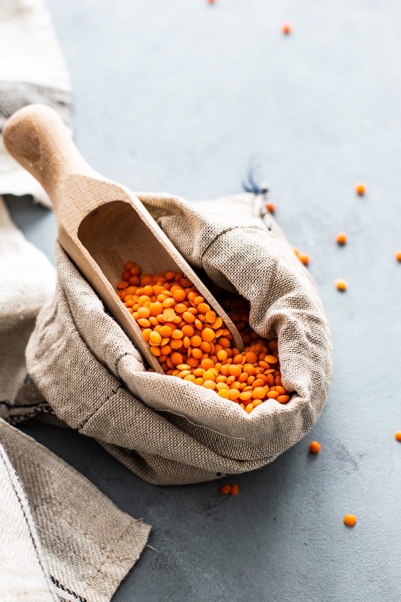 bag of red lentils with wooden scoop
