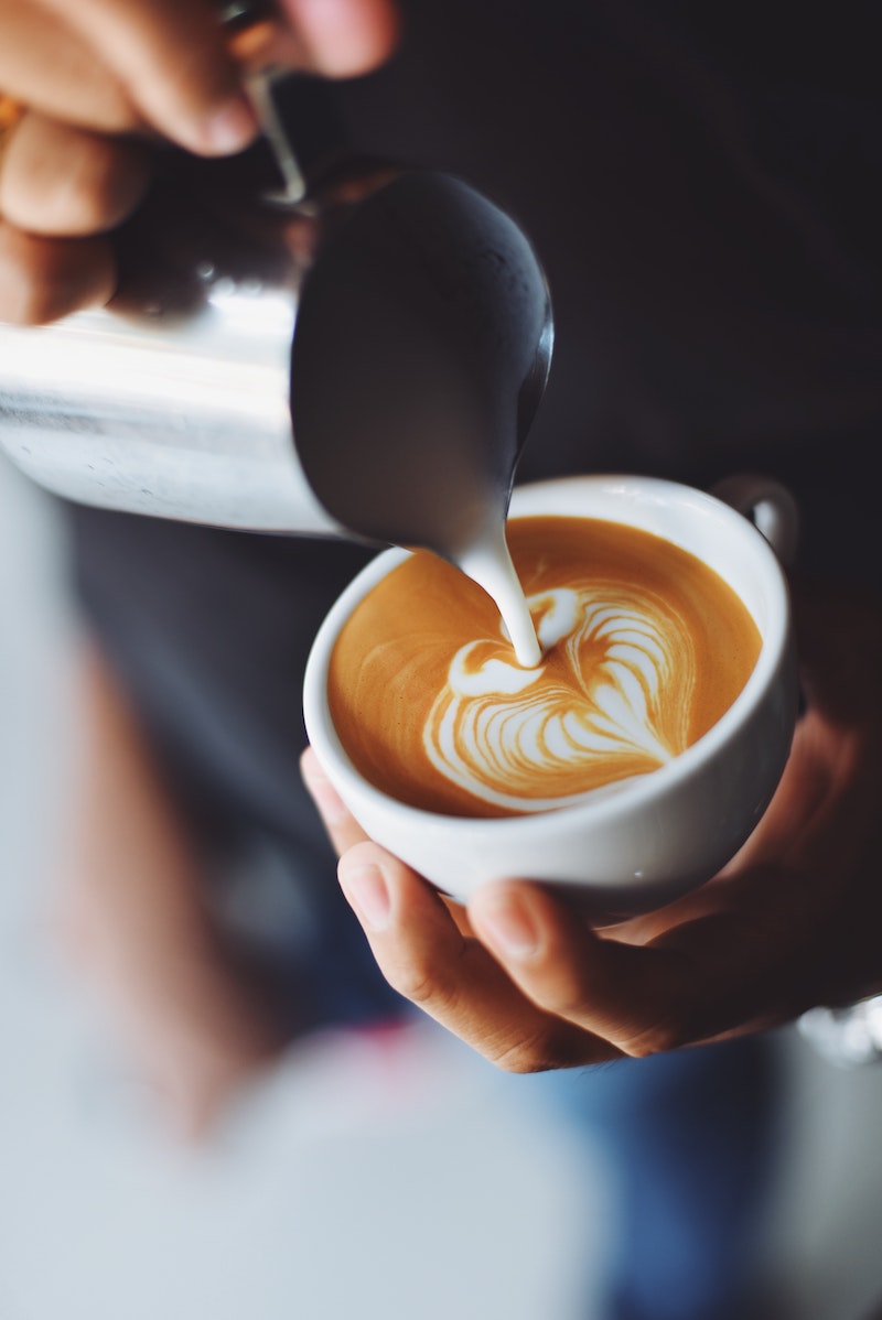 barista pouring milk into coffee cup