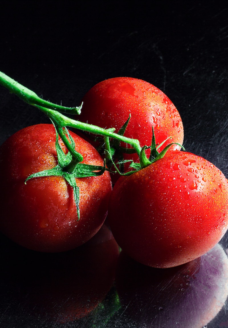 close up of three tomatoes with green stems