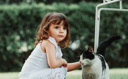girl crouching on the ground petting a cat