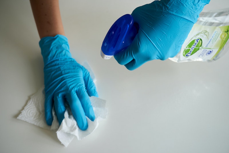 hands in blue gloves disinfecting a surface