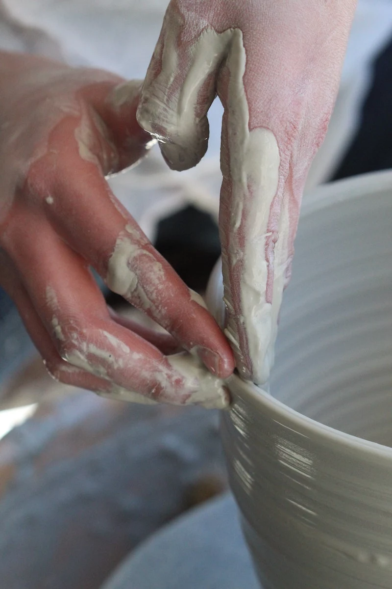 hands molding clay into a shape
