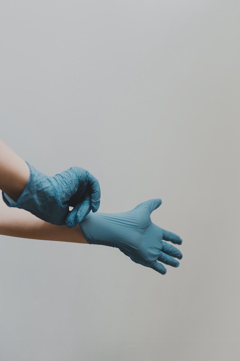 hands putting on blue gloves for cleaning
