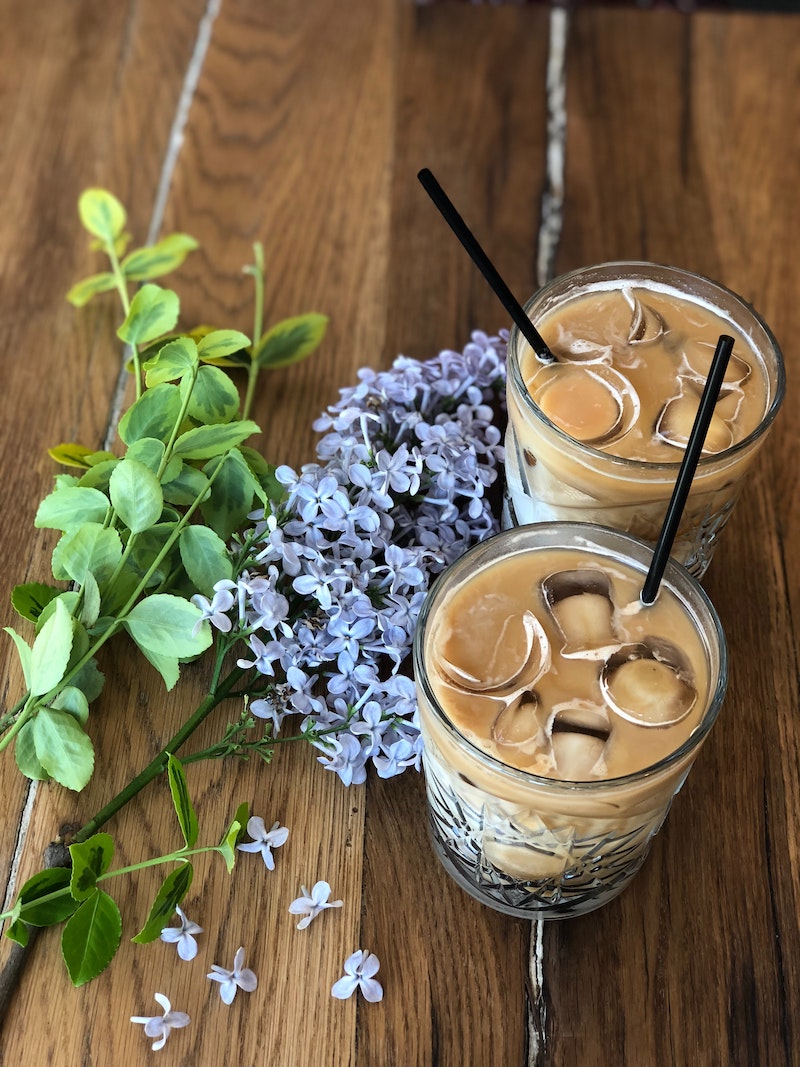 iced coffee with ice and lilac next to them