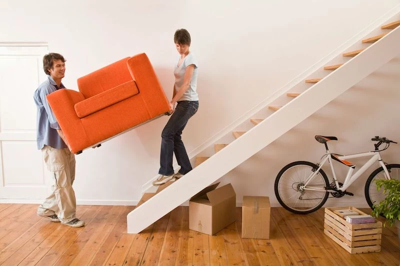 man and woman moving an orange armchair