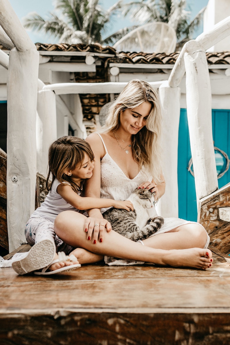mother and child holding and petting a cat