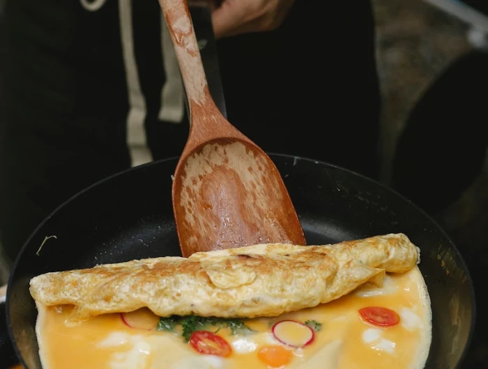 person cooking an omlet with veggies