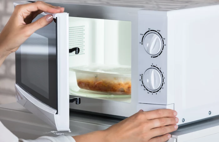 person heating up leftovers in microwave