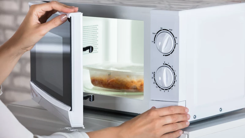 person heating up leftovers in microwave