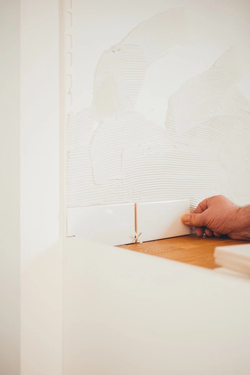 person putting white tiles on a wall